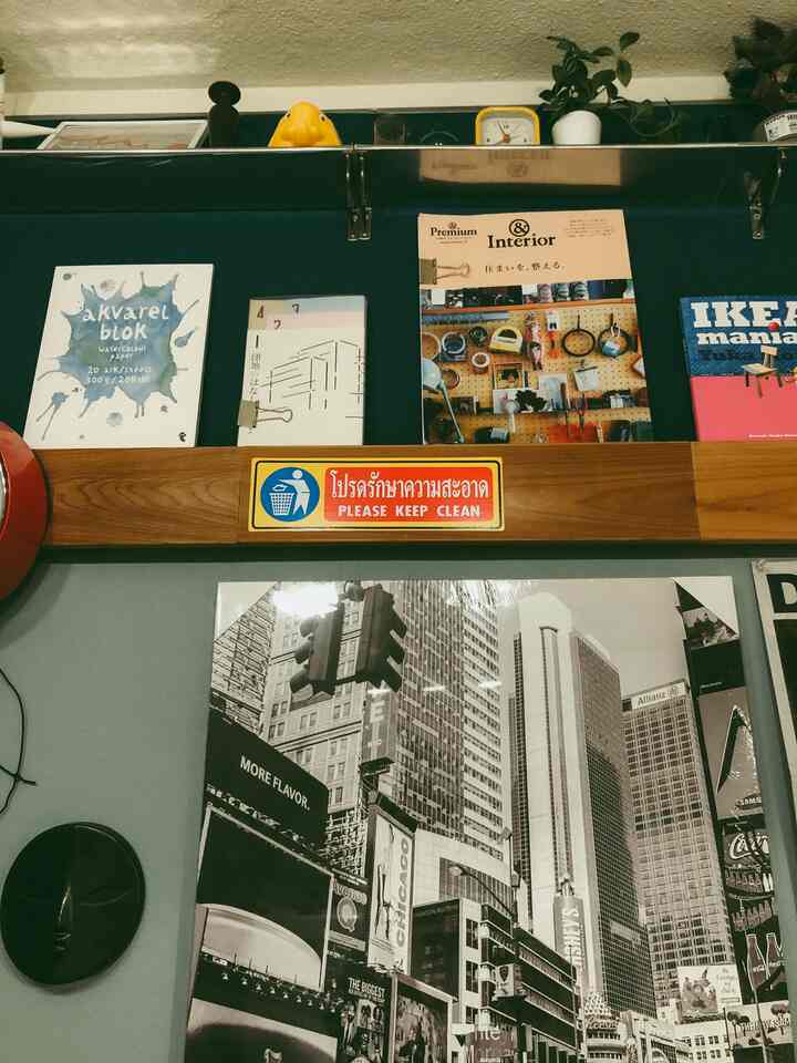 ブルーとウッドトーンの壁にポスターや時計、本、植物が配置された雰囲気のあるウォールデコ空間