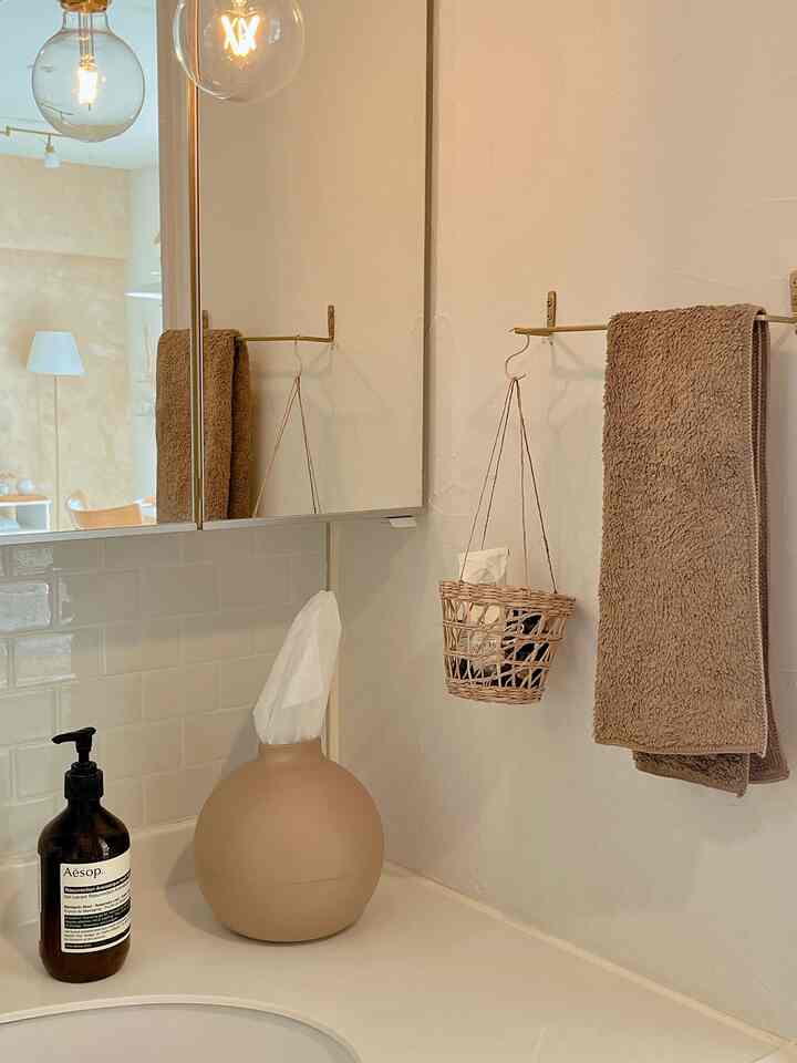 ベージュとナチュラルカラーのトーンのバスルーム、タオル掛けとバス用品が配置された雰囲気のあるインテリア