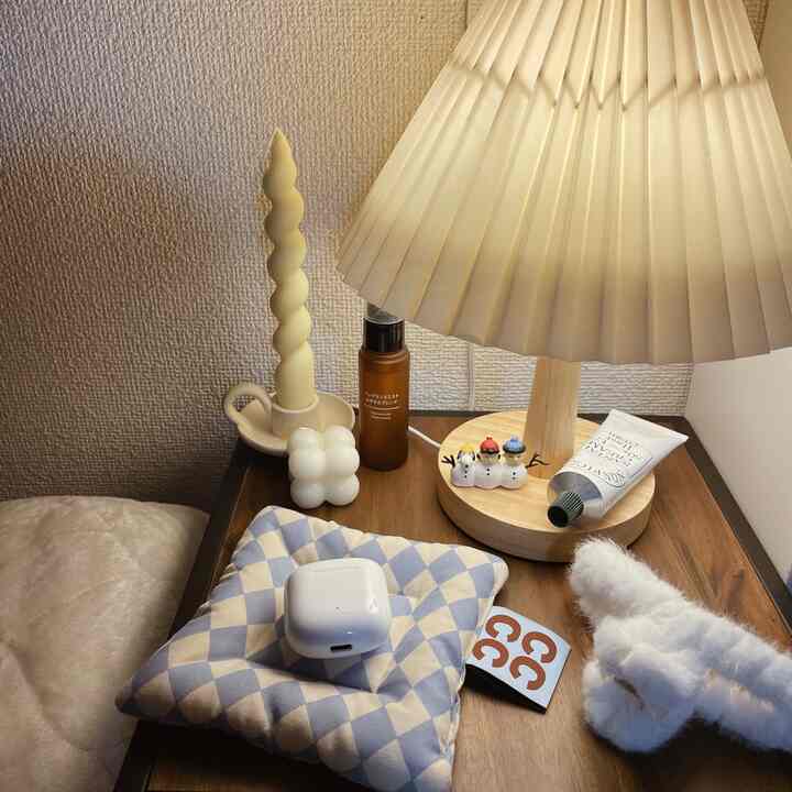 ナチュラルなブラウンのナイトテーブルの上に照明とキャンドル、スキンケア用品が置かれた雰囲気のある寝室コーナー