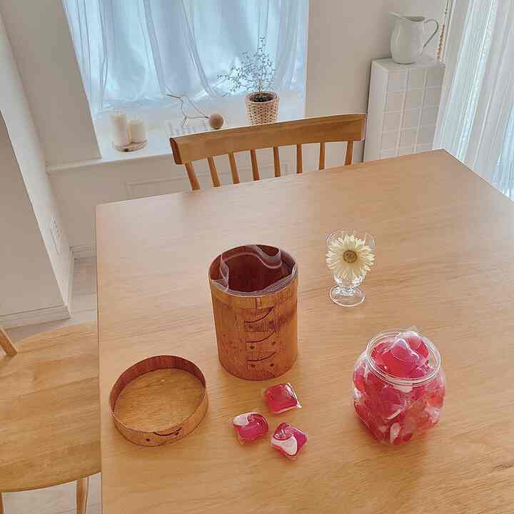 木目調のダイニングテーブルと椅子が配置されたナチュラルでシンプルな空間、白いカーテンと花瓶でアクセントを加えた落ち着いたキッチンダイニング