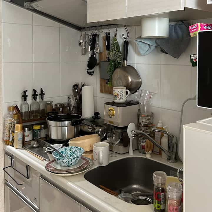 ナチュラルな色調のキッチン、シンクや調理器具、食器が散らかった印象的な空間