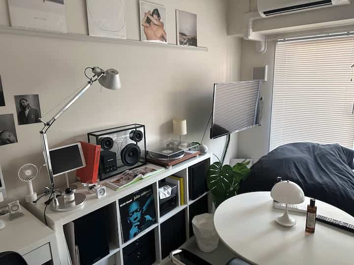 White and black toned studio living room featuring a bean bag sofa, bookshelf, and wall-mounted TV in a minimalist modern space
