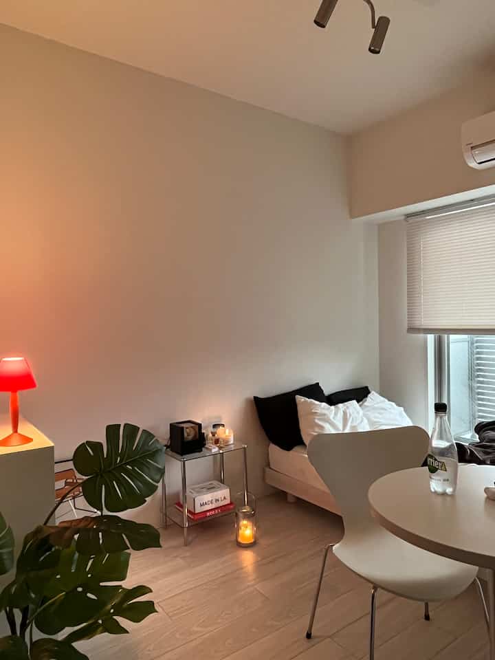 Monotone modern bedroom space featuring a white dining chair and red table lamp with a calm ambiance