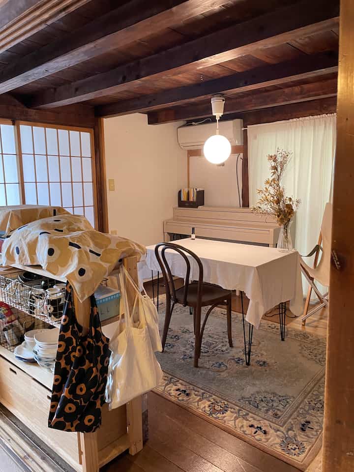 A traditional old folk house style dining room with dark wood tones and white colors, featuring a pendant light and a dining table in a cozy setting