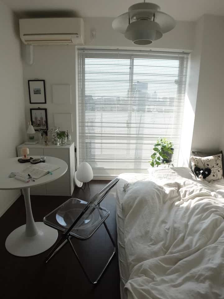 明るい白いトーンと木の床が調和したコンパクトなワンルームの寝室