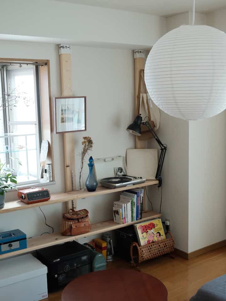 Natural toned small living room featuring DIY wooden shelves with various decorative objects creating a cozy atmosphere