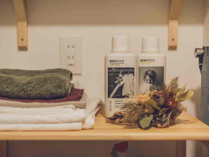 Natural tone entrance space featuring a Muji pine shelf with folded towels and laundry products neatly organized