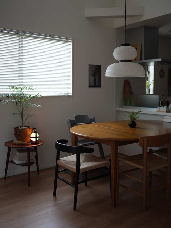 Natural dining room with wood tones and white walls, featuring a wooden round table and chairs in a simple setting
