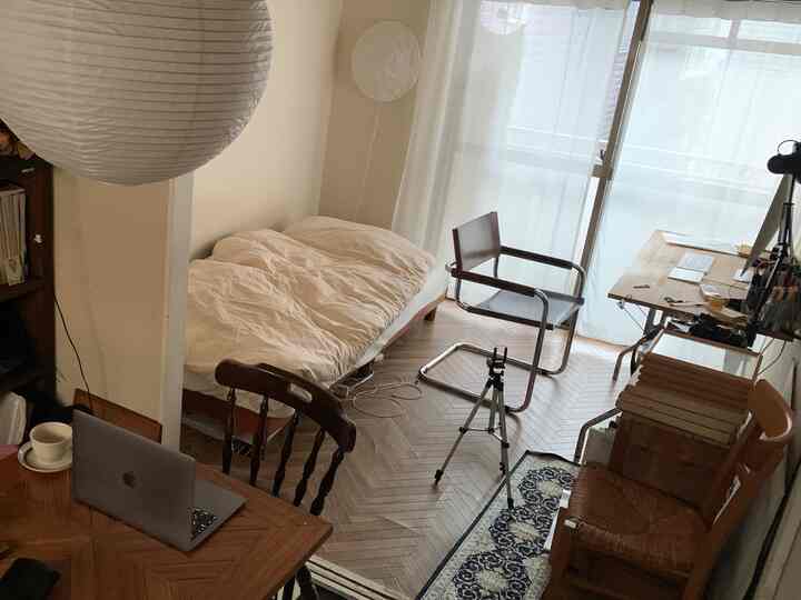 白と木目調の6畳の寝室兼ホームオフィス、ベッドとデスクが配置された自然でモダンな印象的な空間