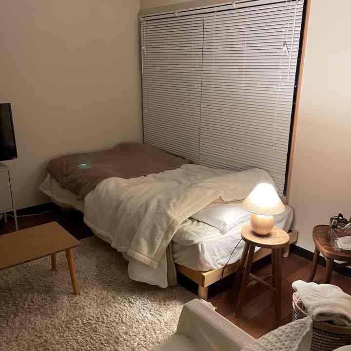 A natural and simple 6-tatami bedroom in white and wood tones, featuring a bed with a nightstand lamp