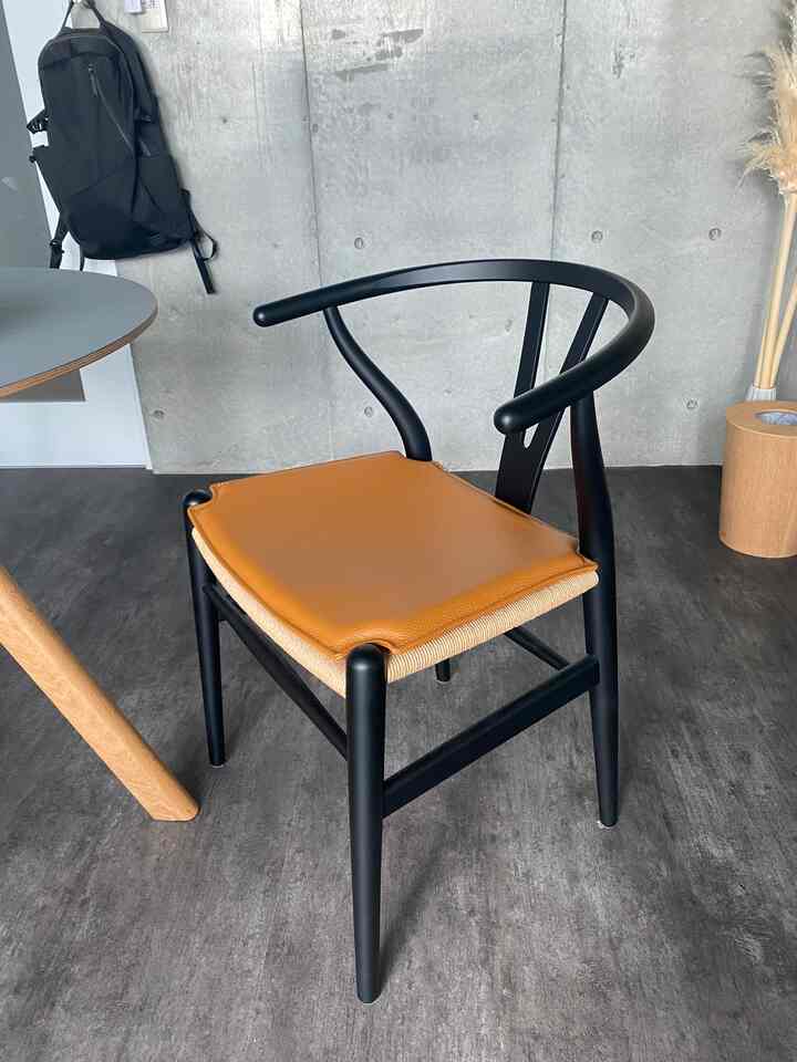 ナチュラルな色調の空間、黒いフレームと茶色いレザーシートのダイニングチェアが置かれたモダンでシンプルなインテリア