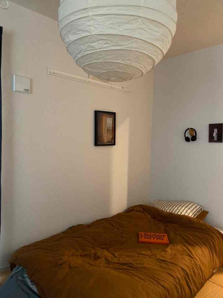 温かみのあるブラウンとホワイトトーンの寝室、シンプルなペンダントライトと壁の装飾が配置された雰囲気のあるインテリア