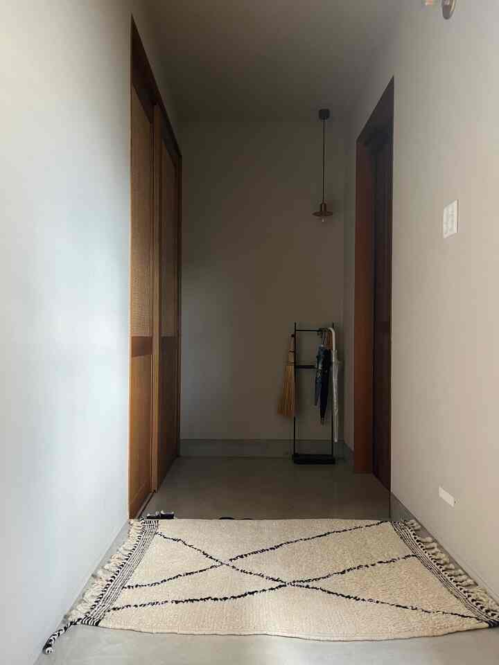 Modern entrance space with beige and gray tones, featuring mortar floor, wood doors, and a simple pendant light with clean interior