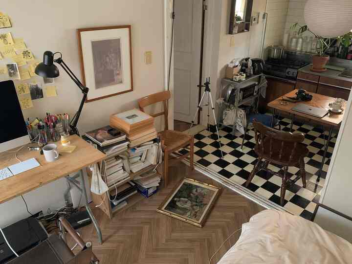 温かみのある木目調と白い壁のコンパクトなキッチンとホームオフィス空間、額縁やデスクが配置された雰囲気のあるインテリア