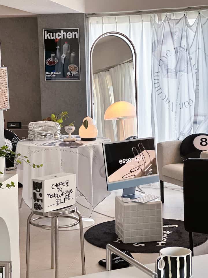 白を基調とした一人暮らし用リビング、iMacとステンレス製スツールが配置されたモダンで清潔感のある空間