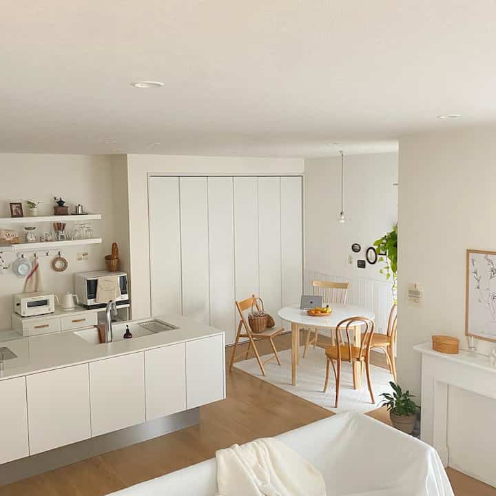 ナチュラルカラーとホワイトのトーンが調和したワンルームのキッチンとダイニング、シンプルでモダンな雰囲気のあるインテリア