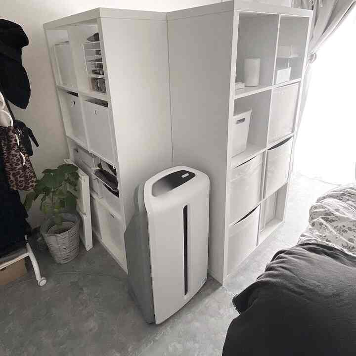 Compact home office space in white and gray tones featuring two shelving units with organized storage in a small room layout