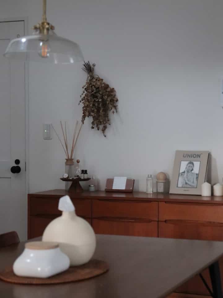 ナチュラルトーンのダイニングルーム、ブラウンの木製家具とテーブルの上にディフューザーが置かれた雰囲気のあるインテリア