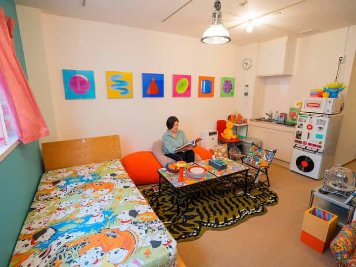 Bright and colorful studio apartment living-bedroom featuring pop art, vibrant decor, and cozy seating elements