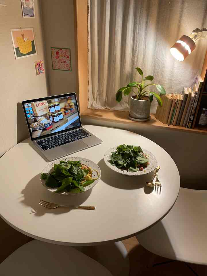 白を基調としたワンルームのダイニングスペース。丸いテーブルと植物、ゴールドのカトラリーが配置され、雰囲気のあるおうちカフェ空間。