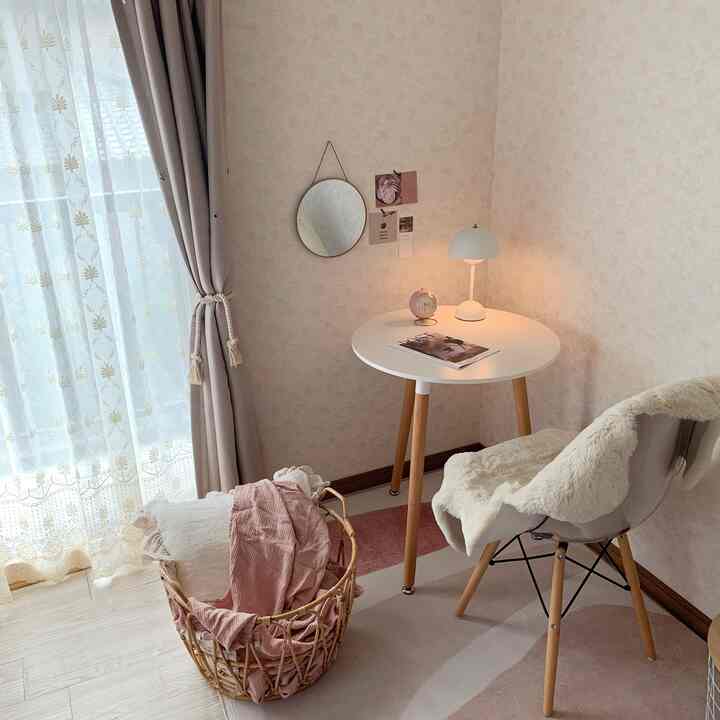 白とナチュラルカラーの一人暮らしの小さな部屋、丸いデスクと椅子が配置されたシンプルで居心地の良いインテリア