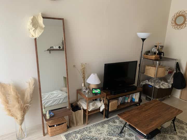 Natural tones and white-walled living room featuring wooden mirror and side table, TV stand, and floor lamp creating cozy atmosphere