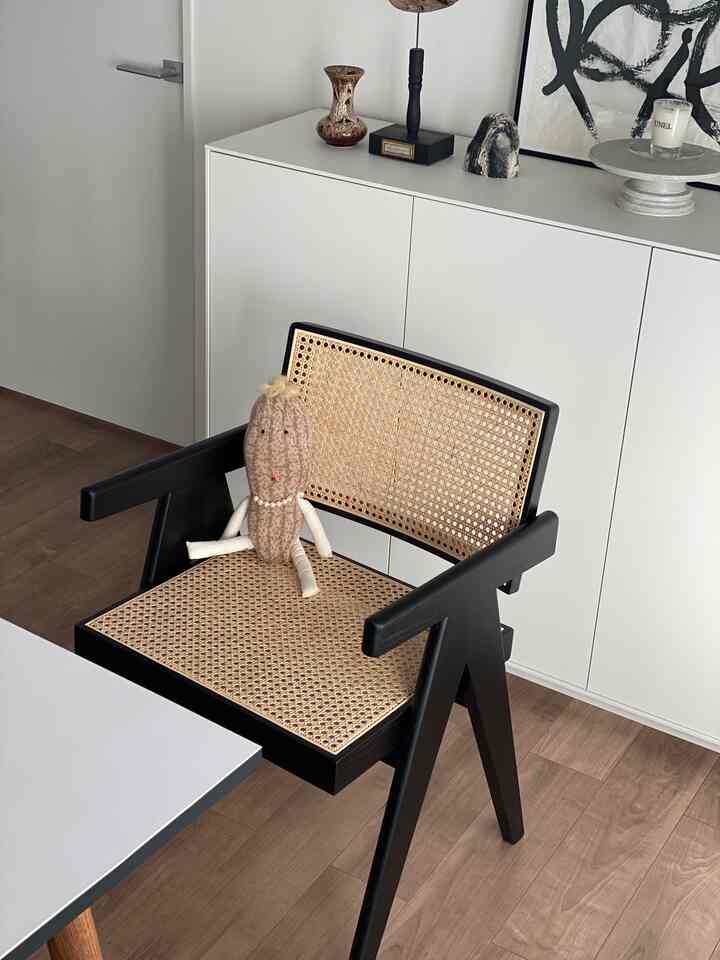 黒と茶色のトーンが特徴的なダイニングルーム、ピエール・ジャンヌレのラタンチェアが配置されたシンプルでモダンなインテリア