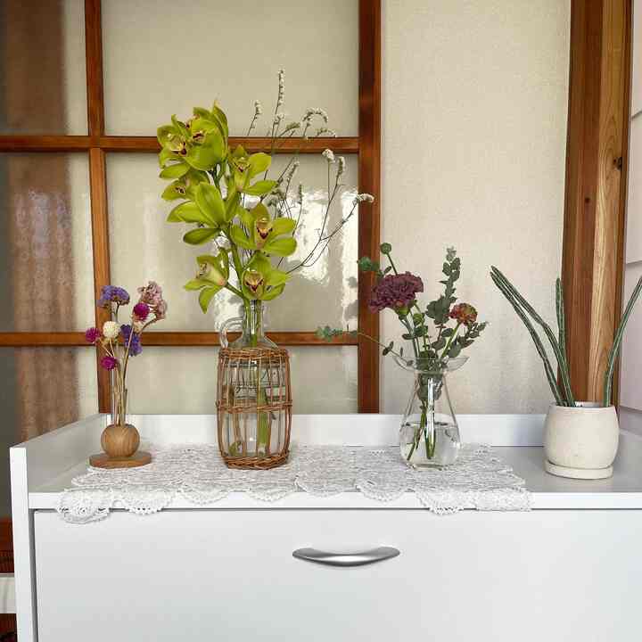 白を基調とした玄関、様々な花瓶と植物が置かれたナチュラルでシンプルな雰囲気のインテリア