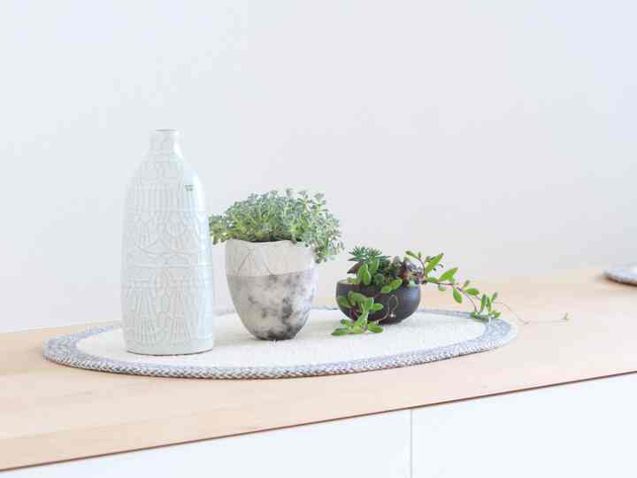 Minimal entrance space with plants and vase placed on wood tone shoe cabinet under white wall