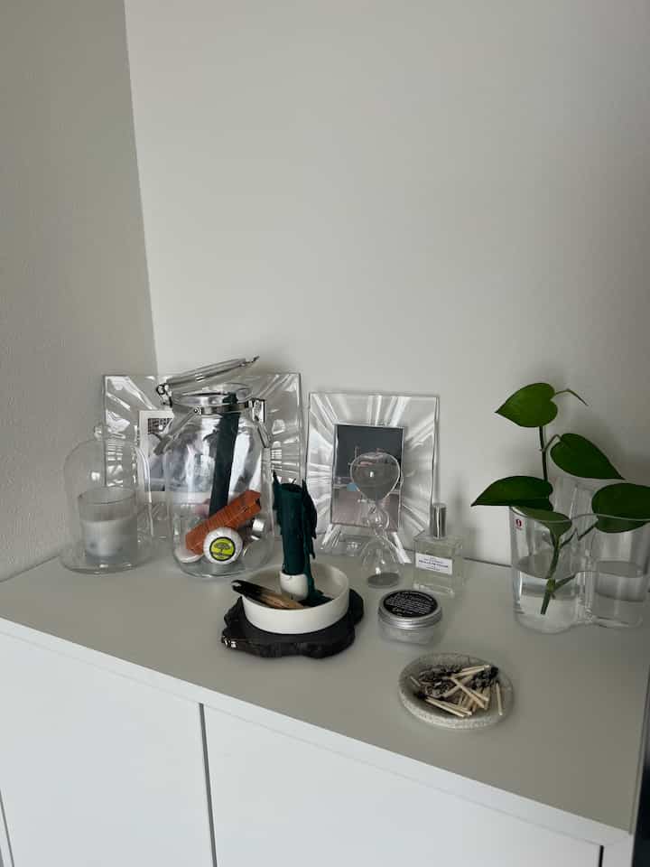 白を基調とした収納キャビネットの空間に、透明なガラスの花瓶やオブジェが配置されたミニマルでナチュラルな雰囲気のインテリア