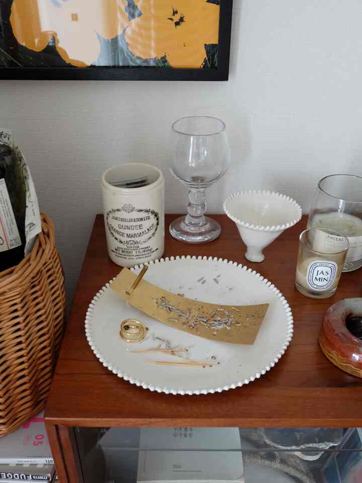 ナチュラルな木目調キャビネットの上にインセンスホルダーと白いプレート、キャンドルが置かれた落ち着いたインテリア空間