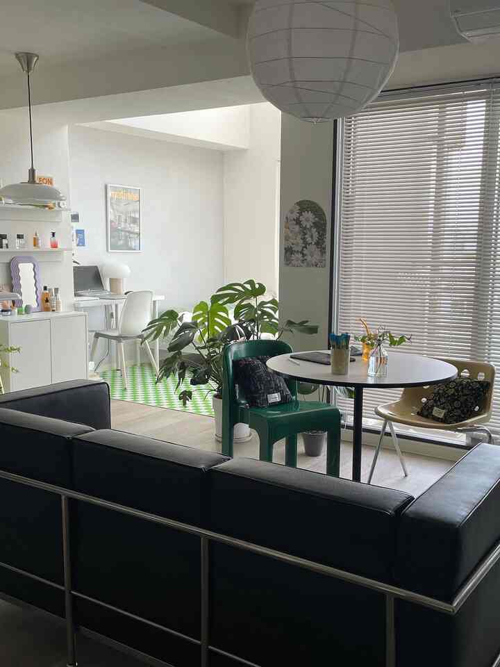 White and black toned studio apartment living room with home office, featuring plants and pendant lights in a natural interior style