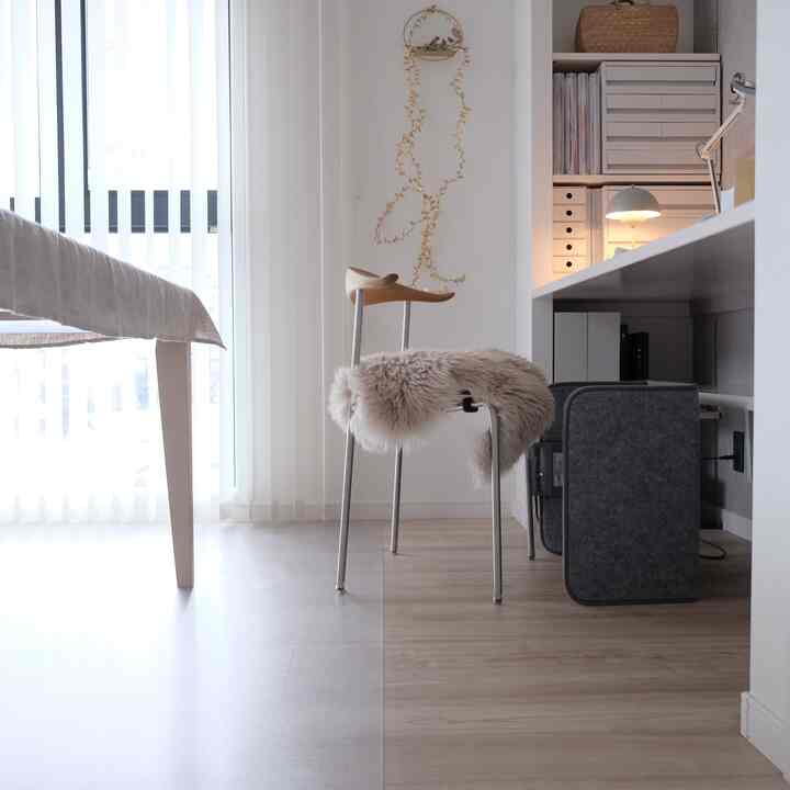 Natural modern home office with white and wood tones, featuring a desk and stool creating a cozy workspace