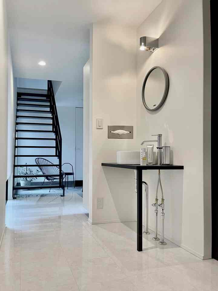 白と黒のトーンでまとめられた玄関脇のセカンド洗面が配置されたモダンで清潔感のあるインテリア