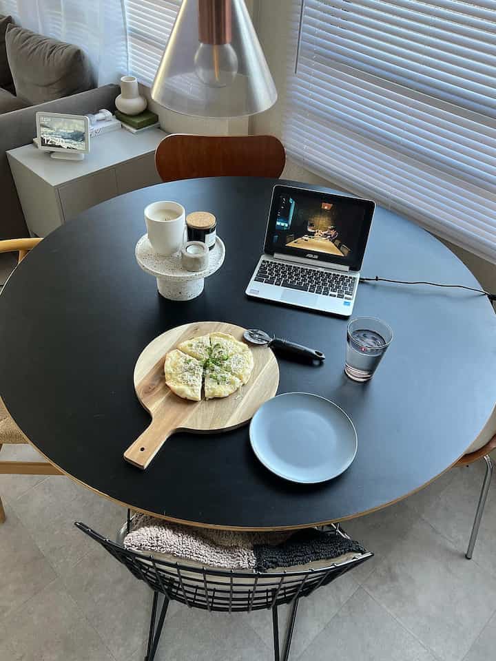 Modern two-person dining space with light gray flooring and black round dining table