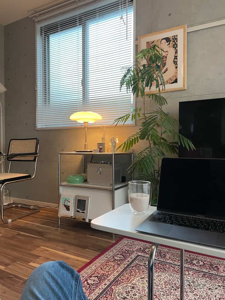 木目調の床と北欧風のホームオフィス空間、サイドテーブルと植物が配置された温かみのあるリビング