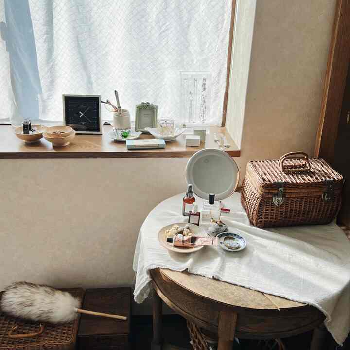 Natural color and wood tone powder room featuring a round vanity table by a curtained window with cozy atmosphere