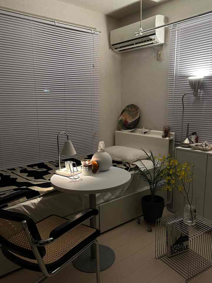 ベージュとホワイトのトーンの小さな寝室、シンプルな家具と花瓶が調和する雰囲気のあるインテリア