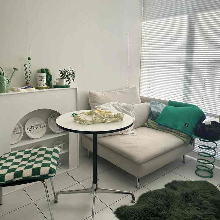 クリームホワイトの壁とベージュのソファ、グリーンのアクセントが配置されたモダンなリビングルーム