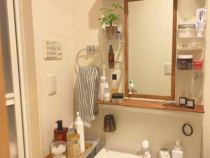 White and beige toned bathroom featuring wooden framed mirror and assorted toiletries creating a cozy space
