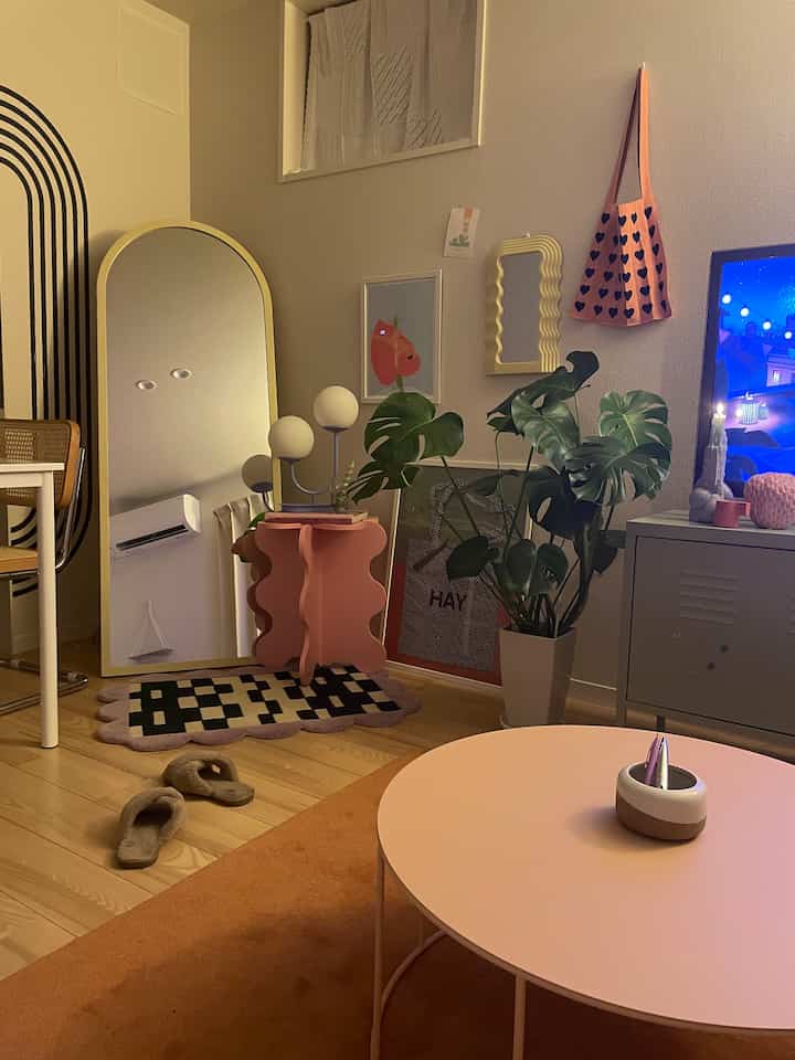 Natural color and orange-toned living room featuring a large plant and curvy side table creating a cozy atmosphere
