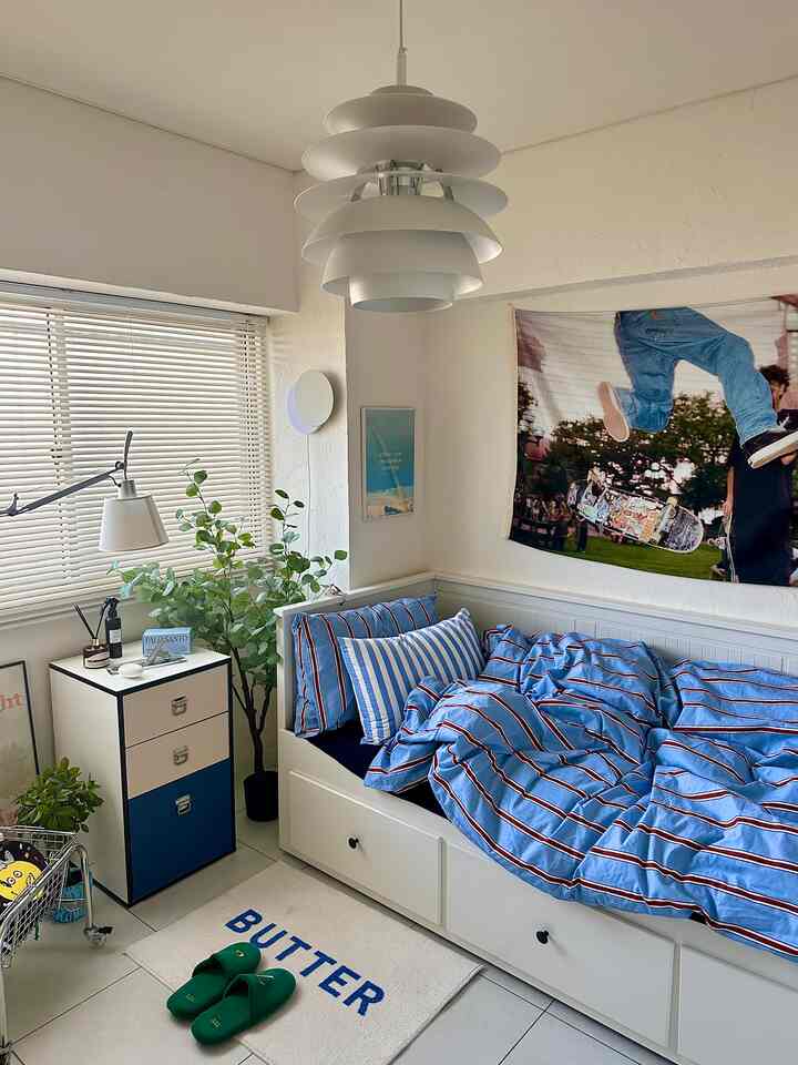 白と青の色調の寝室、3段チェストと植物が配置された落ち着いたモダンなインテリア