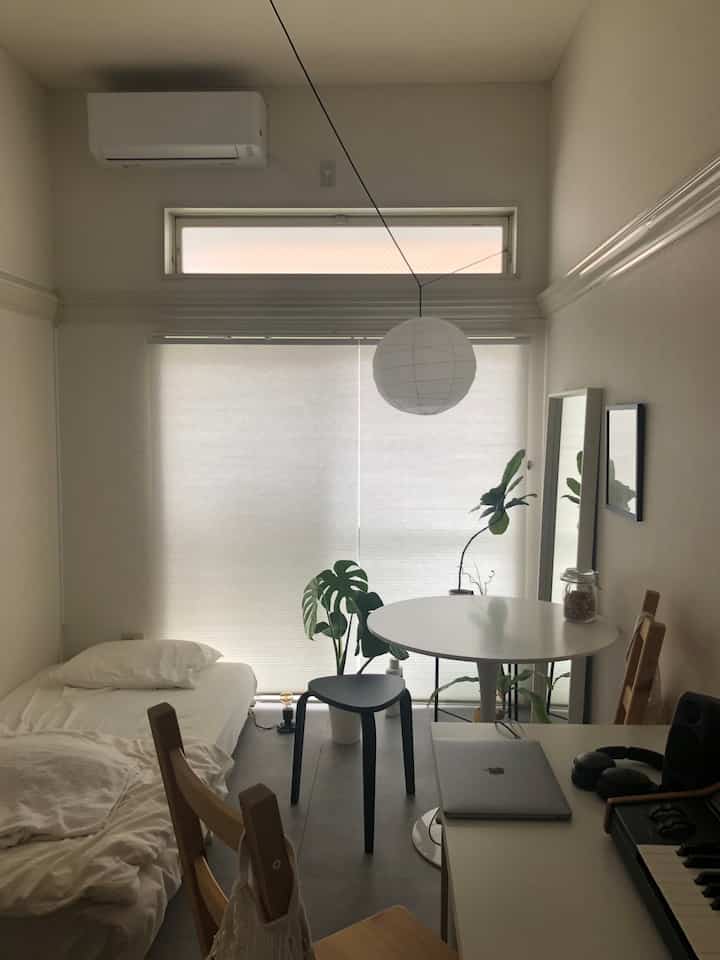 White and black dominant single household bedroom featuring a simple round table and stool with a clean atmosphere