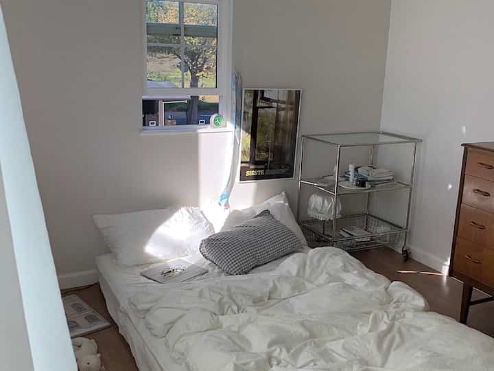 White-toned small bedroom featuring a mattress and pillows on the floor, creating a cozy atmosphere.