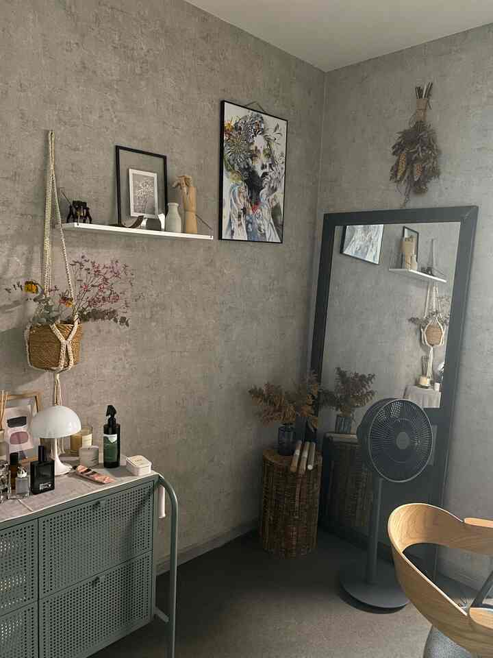 グレーの壁紙と木目調家具が配されたナチュラルな雰囲気の狭い部屋、スツール・棚・大きな鏡が印象的な空間