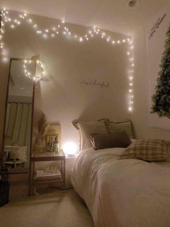 White and beige toned bedroom featuring bed and string lights, simple and cozy atmosphere