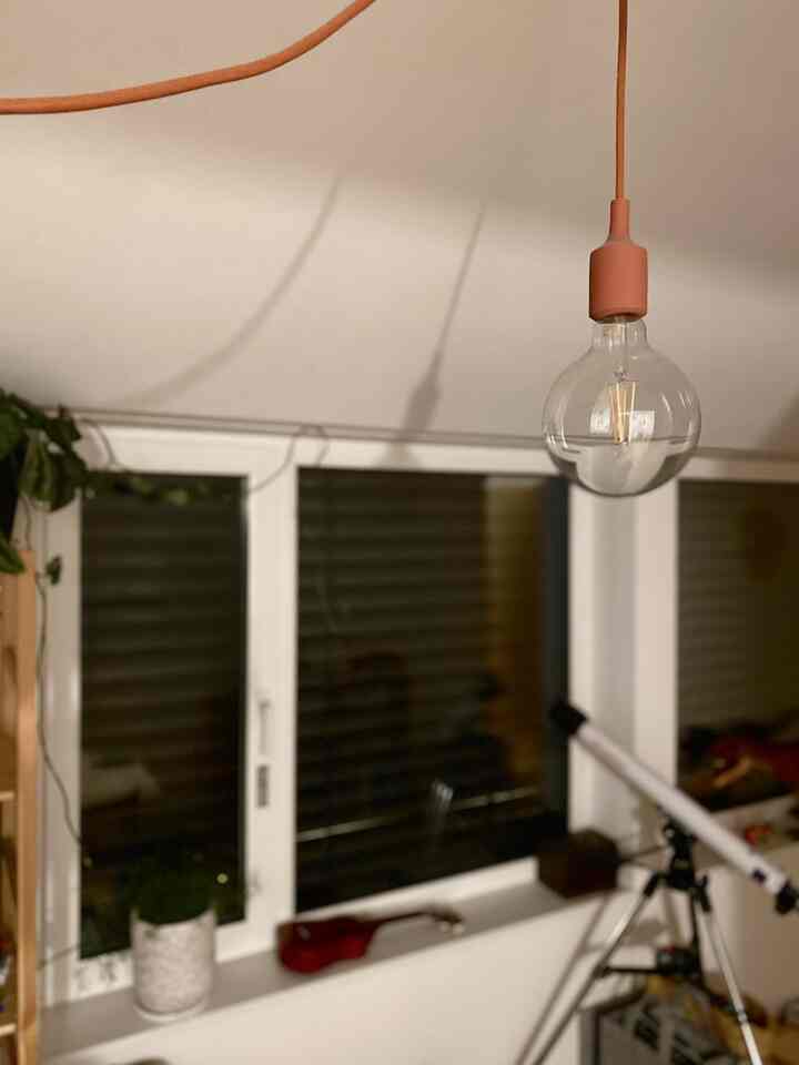 白とナチュラルな色調の子供部屋、窓際に天体望遠鏡とペンダントライトが配置された温かみのある雰囲気のインテリア