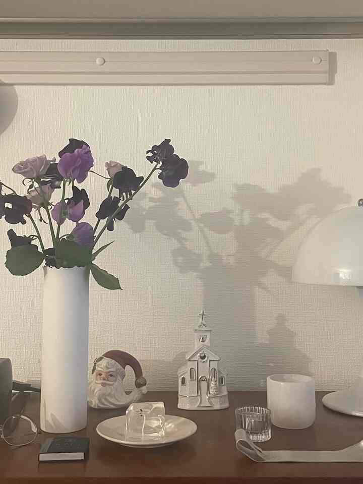 Cozy space with white walls and wooden chest featuring vintage decor and a vase of purple flowers