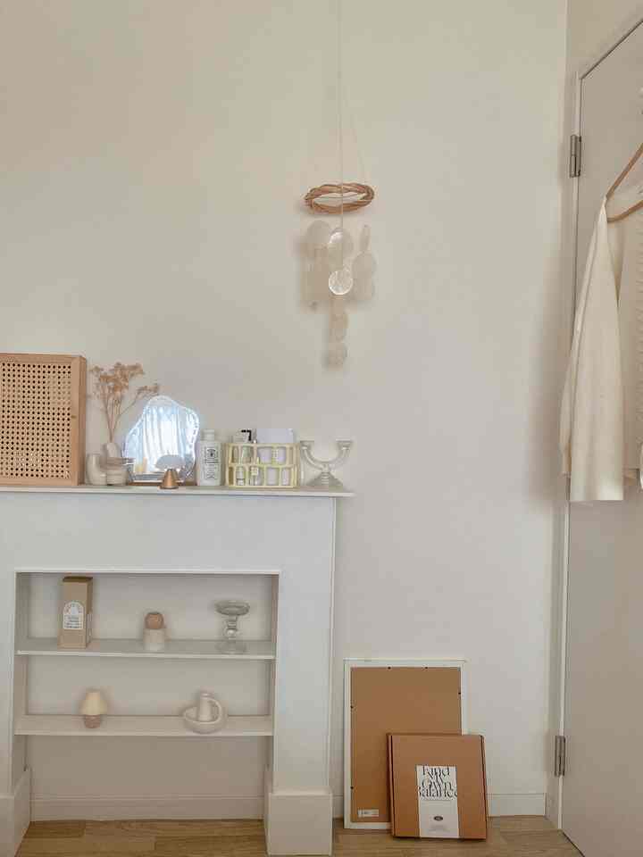 ナチュラルな色調の寝室の壁とドア、棚に置かれたキャンドルスタンドとドライフラワーが調和する落ち着いたインテリア