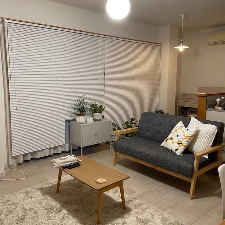 白い壁と木目調の家具が配置された二人暮らし用リビング、ナチュラルモダンスタイルの清潔で居心地の良い空間